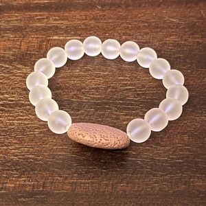 Pink beaded bracelet with oval lava stone.